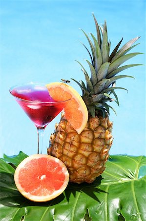 Tropical cocktail with fruit and blue water background; don't miss the wasp on the grapefruit garnish Stock Photo - Budget Royalty-Free & Subscription, Code: 400-03957557