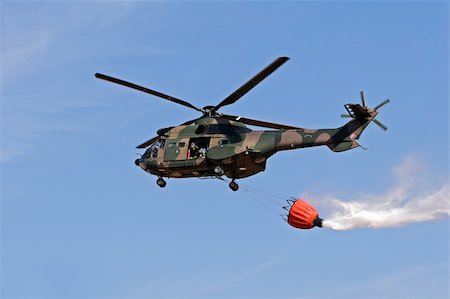 simsearch:673-02140713,k - Military helicopter  with a bucket filled with water to fight a forest fire Foto de stock - Royalty-Free Super Valor e Assinatura, Número: 400-03950905
