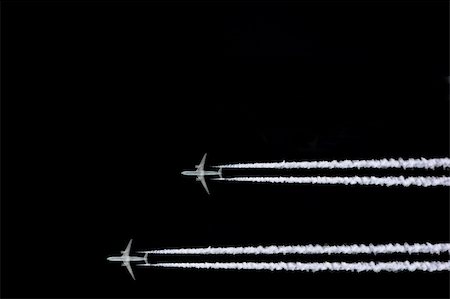 Two jet aircraft flying in a horizontal and parallel formation with smoke trails, set against a black sky background. Stock Photo - Budget Royalty-Free & Subscription, Code: 400-03950942