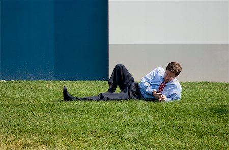 Businessman using Cell Phone while Lying on Grass Stock Photo - Budget Royalty-Free & Subscription, Code: 400-03952856