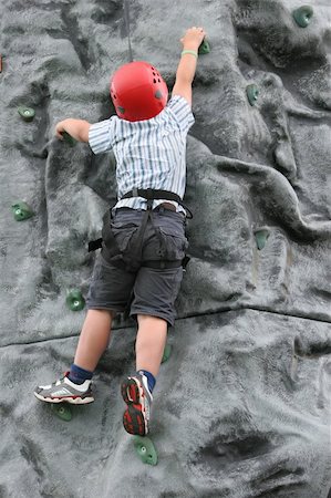simsearch:400-03936239,k - Young boy climbing on a rock training face, wearing a safety harness and red helmet. Stockbilder - Microstock & Abonnement, Bildnummer: 400-03953216