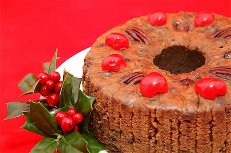 plum pudding - Closeup view of a moist, delicious holiday fruitcake garnished with holly and photographed against a bright red background. Stock Photo - Budget Royalty-Free & Subscription, Code: 400-03966832