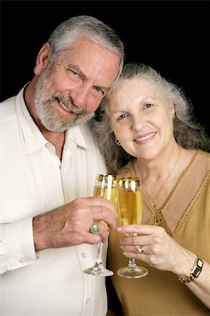 Good looking mature couple toasting the season with champagne.  Black background. Stock Photo - Budget Royalty-Free & Subscription, Code: 400-03967362