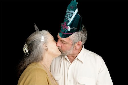Happy mature couple exchanging a passionate New Years kiss.  Isolated on black. Stock Photo - Budget Royalty-Free & Subscription, Code: 400-03967396