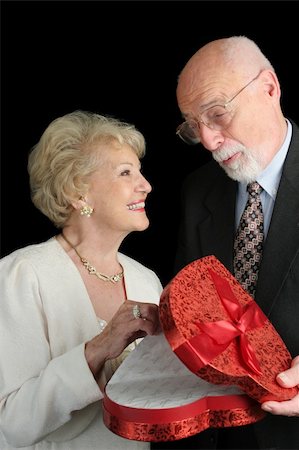 A handsome senior man giving a valentine gift to his beautiful wife.  Black background. Stock Photo - Budget Royalty-Free & Subscription, Code: 400-03967406