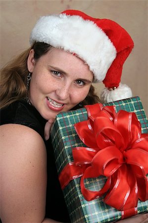 simsearch:400-07107254,k - A young, pretty woman holding a Christmas gift she just received. Photographie de stock - Aubaine LD & Abonnement, Code: 400-03967456