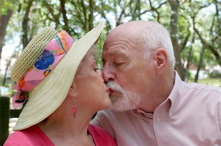 simsearch:400-05711437,k - An attractive senior couple kissing outdoors under a canopy of trees. Stock Photo - Budget Royalty-Free & Subscription, Code: 400-03969241