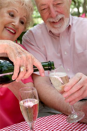 A senior couple - the wife is pouring champagne for the husband.  (focus is on bottle neck & champagne in glass) Stock Photo - Budget Royalty-Free & Subscription, Code: 400-03969274