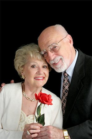 simsearch:400-03967470,k - A handsome, romantic, senior couple holding a red rose, posing against a black background. Fotografie stock - Microstock e Abbonamento, Codice: 400-03969301