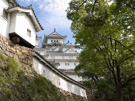 View of the main tower of Himeji Castle in the distance between one of the lower walls  and trees of the castle grounds during the daytime Stock Photo - Budget Royalty-Free & Subscription, Code: 400-03969507