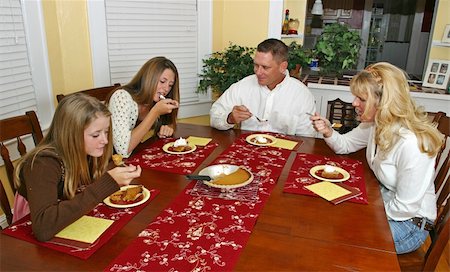 simsearch:400-04779556,k - A family sitting around the dinner table enjoying pumpkin pie. Photographie de stock - Aubaine LD & Abonnement, Code: 400-03969761
