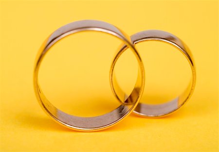 simsearch:400-04499320,k - Gold wedding rings on yellow light bacground Fotografie stock - Microstock e Abbonamento, Codice: 400-03960461