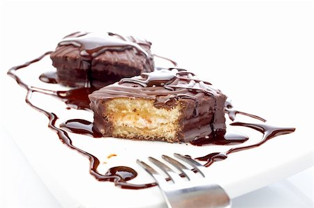 Two chocolate cupcakes with syrup and the fork on white plate. Shallow DOF Stock Photo - Budget Royalty-Free & Subscription, Code: 400-03963962