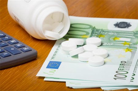 dollar sign of pills - Open bottle of pills on top of money, focus on bottom pills and calculator Stock Photo - Budget Royalty-Free & Subscription, Code: 400-03975724