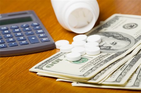 dollar sign of pills - Open bottle of pills on top of money, focus on bottom pills and calculator Stock Photo - Budget Royalty-Free & Subscription, Code: 400-03975722