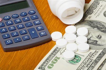 dollar sign of pills - Open bottle of pills on top of money, focus on bottom pills and calculator Stock Photo - Budget Royalty-Free & Subscription, Code: 400-03975723