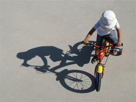 simsearch:400-04890875,k - A little boy riding a bike with his shadow on a gray background Stock Photo - Budget Royalty-Free & Subscription, Code: 400-03978803