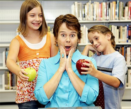 female teacher eating apple - A teacher surprised by two students with apples for her. Foto de stock - Super Valor sin royalties y Suscripción, Código: 400-03970515