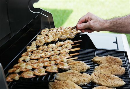 food for the fourth - Shrimp and chicken on a barbecue grill.  A man's hand is flipping a skewer of shrimp.  Focus on shrimp being turned. Stock Photo - Budget Royalty-Free & Subscription, Code: 400-03970899