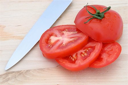 simsearch:700-00168950,k - A sliced tomato and a knive on a wood cutting board. Photographie de stock - Aubaine LD & Abonnement, Code: 400-03970982