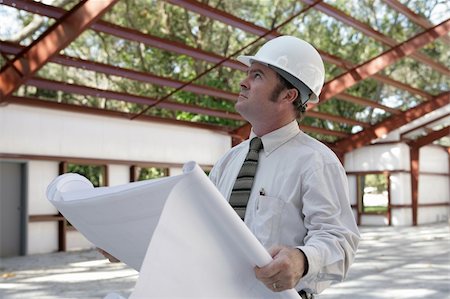 simsearch:400-04485408,k - A construction inspector holding blueprints and looking at the roof beams of a steel building in progress. Stock Photo - Budget Royalty-Free & Subscription, Code: 400-03971075