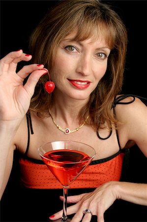 A beautiful woman drinking a cosmopolitan and holding offering the cherry for you to eat. Photographie de stock - Aubaine LD & Abonnement, Code: 400-03971665