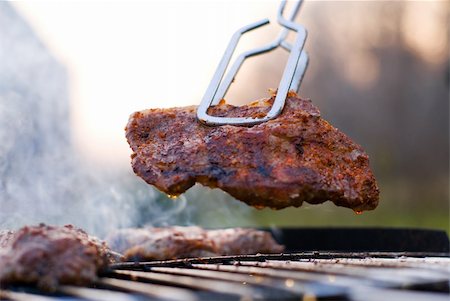 simsearch:400-03930949,k - Delicious chuck steak on the grill in metal tongs. Shallow depth of field. Stockbilder - Microstock & Abonnement, Bildnummer: 400-03971862