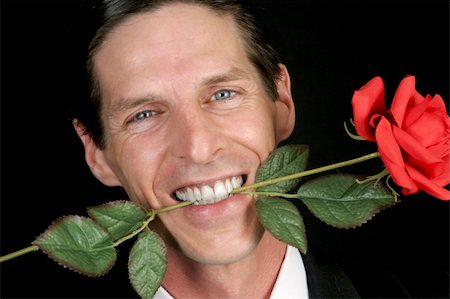 simsearch:400-04171391,k - A handsome, romantic man holding a rose in his teeth - black background. Stock Photo - Budget Royalty-Free & Subscription, Code: 400-03972442