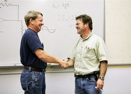 An adult student shaking hands with his teacher in front of the white board. Stock Photo - Budget Royalty-Free & Subscription, Code: 400-03972752