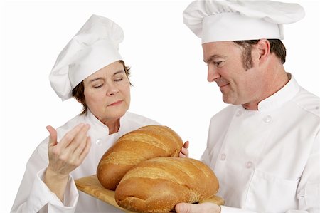Mature female chef evaluating the bread of a student.  Isolated on white. Stock Photo - Budget Royalty-Free & Subscription, Code: 400-03972776