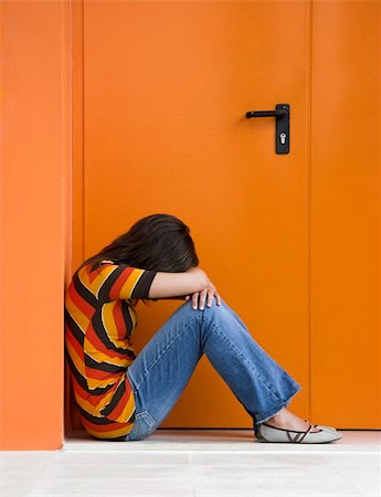 depressed woman in the street - Loneliness woman on a orange door with hands over the knees Stock Photo - Budget Royalty-Free & Subscription, Code: 400-03986481