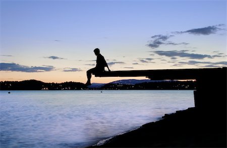 A young person sitting on a dock at dusk, at the fjord in Oslo, Norway Stock Photo - Budget Royalty-Free & Subscription, Code: 400-03987569