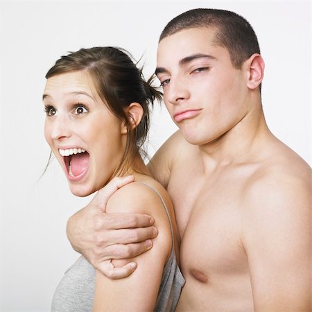 A portrait of a young couple with playful expressions on their face. The man is hugging the woman from behind . Stock Photo - Budget Royalty-Free & Subscription, Code: 400-03988431