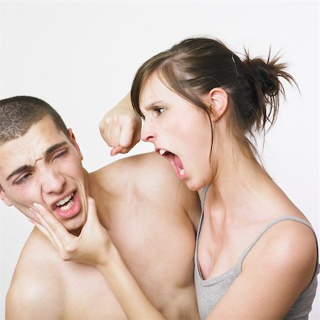 A young couple fighting on a white background . The woman is holding the mans jaw in one hand and her other hand is raised in a fist. The man is cringing in anticipation of the punch. Photographie de stock - Aubaine LD & Abonnement, Code: 400-03988474