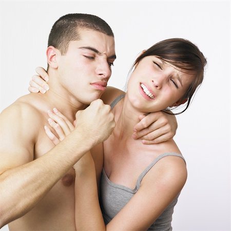 A young couple on a white background. They are holding each other and look as if they are having a fight. The man is holding his fist up threateningly, but the woman has a hint of a smile on her face. Maybe they are just playing. Both models have their eyes closed. Photographie de stock - Aubaine LD & Abonnement, Code: 400-03988478