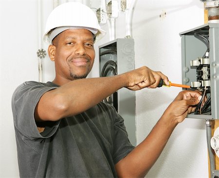simsearch:400-04485314,k - Handsome african american electrician working on a breaker panel.  Model is an actual electrician performing work according to industry safety and code standards. Fotografie stock - Microstock e Abbonamento, Codice: 400-03988979