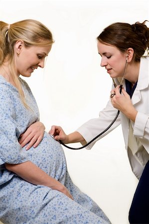 Pregnant blond woman being examined by a female doctor holding a stethoscope on the stomach Stock Photo - Budget Royalty-Free & Subscription, Code: 400-03994165