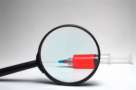 A medical syringe under a magnifying glass. Foto de stock - Super Valor sin royalties y Suscripción, Código: 400-03996173