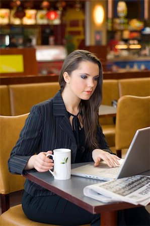 pretty woman sitting in a cafe with a cup of tea working on laptop Stock Photo - Budget Royalty-Free & Subscription, Code: 400-03996846