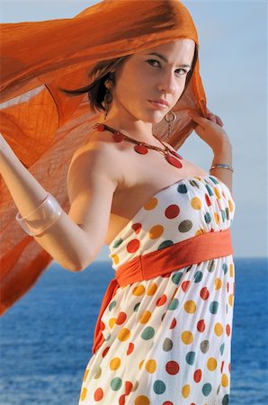 simsearch:400-04624187,k - Fashion model holding oragne clouth against ocean background Fotografie stock - Microstock e Abbonamento, Codice: 400-03997179