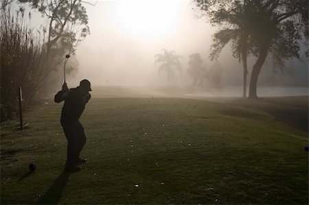 Early morning golfers silhouetted in a dense fog with a rising sun Foto de stock - Royalty-Free Super Valor e Assinatura, Número: 400-03997922
