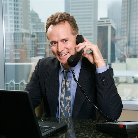simsearch:400-04186486,k - Middle-aged Caucasian male on phone in office with skyline in background. Stock Photo - Budget Royalty-Free & Subscription, Code: 400-03998254