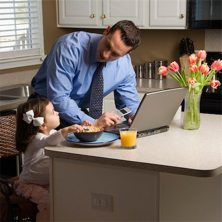Caucasian father in suit using laptop computer with daughter eating breakfast in kitchen. Stock Photo - Budget Royalty-Free & Subscription, Code: 400-03998298