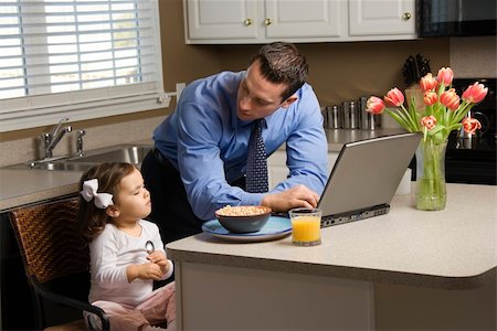 Caucasian father in suit using laptop computer with daughter eating breakfast in kitchen. Stock Photo - Budget Royalty-Free & Subscription, Code: 400-03998299