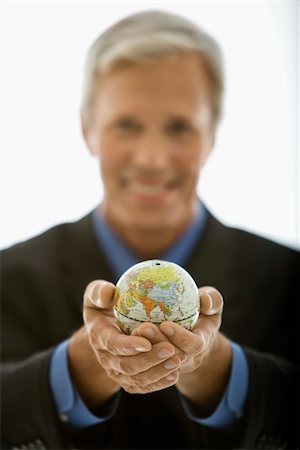 Selective focus of Caucasian middle aged businessman smiling and holding globe towards viewer. Stock Photo - Budget Royalty-Free & Subscription, Code: 400-03999295