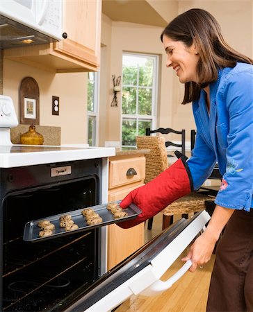 Side view of Hispanic mid adult woman putting cookies into oven. Stock Photo - Budget Royalty-Free & Subscription, Code: 400-03999368