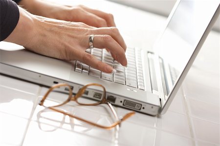 simsearch:400-07546122,k - Female hands typing on the keyboard of the laptop with eyeglasses nearby. Stock Photo - Budget Royalty-Free & Subscription, Code: 400-03999655