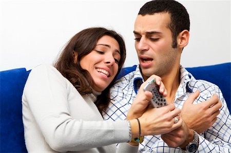 young couple watching tv and fighting to get the remote control Stock Photo - Budget Royalty-Free & Subscription, Code: 400-03993314