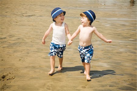 Twin Boys Walking Hand in Hand on Beach Foto de stock - Sin royalties Premium, Código: 600-04223559
