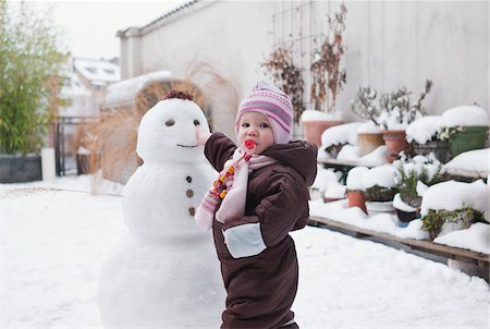 Petite fille jouant avec le bonhomme de neige dans la Cour Photographie de stock - Premium Libres de Droits, Code: 600-04425029